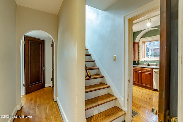 staircase with wood-type flooring and sink