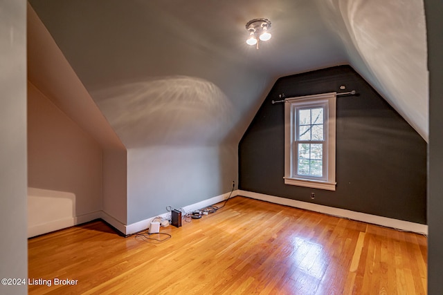 additional living space featuring light hardwood / wood-style floors and vaulted ceiling