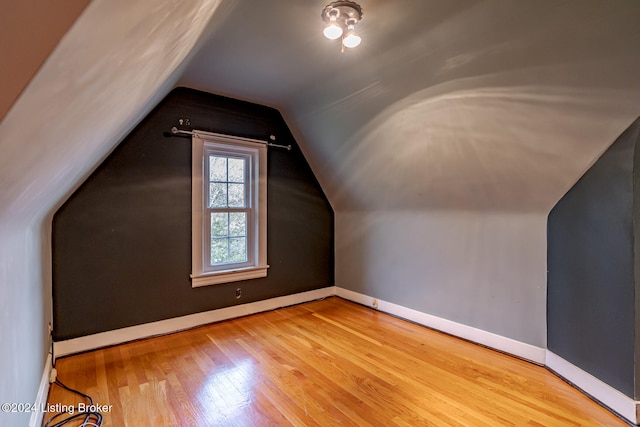 additional living space with light hardwood / wood-style floors and lofted ceiling