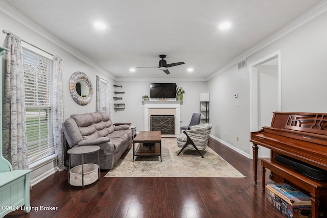 living room featuring dark hardwood / wood-style floors, ceiling fan, ornamental molding, and a tiled fireplace