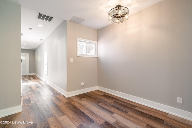 unfurnished room featuring hardwood / wood-style floors and an inviting chandelier