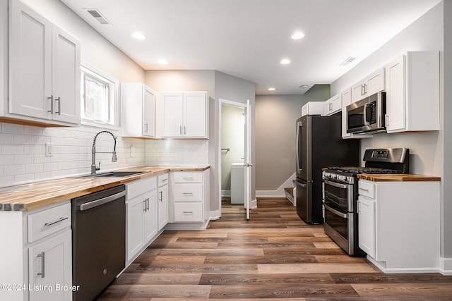 kitchen with butcher block countertops, sink, white cabinets, and appliances with stainless steel finishes