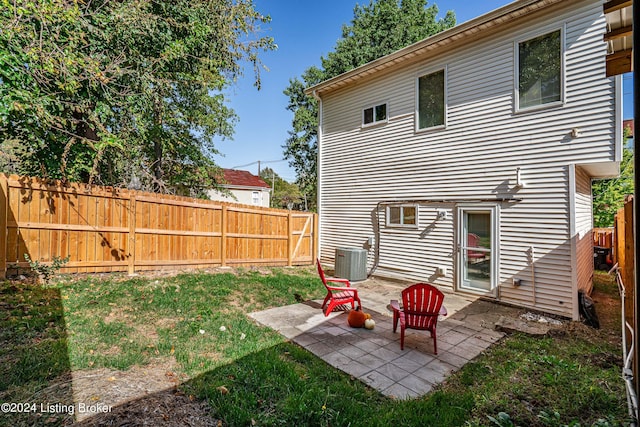 back of property with central air condition unit, a patio area, and a lawn