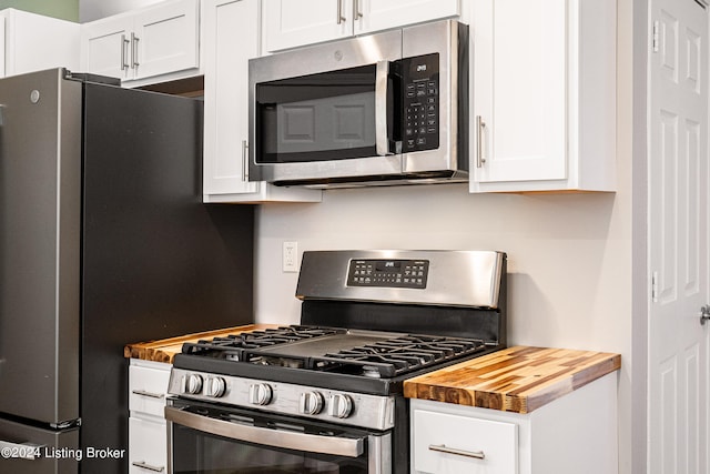 kitchen with white cabinets, wood counters, and appliances with stainless steel finishes