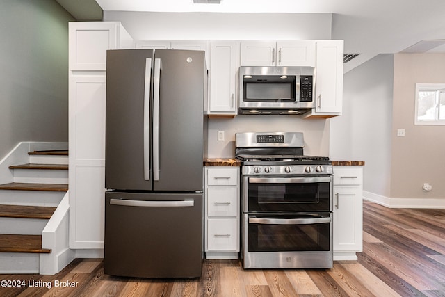 kitchen with white cabinets, wood-type flooring, and appliances with stainless steel finishes