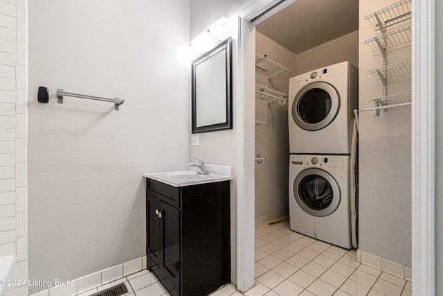 laundry area with stacked washer and dryer, light tile patterned floors, and sink