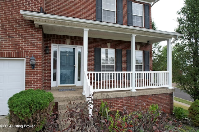 entrance to property featuring covered porch and a garage