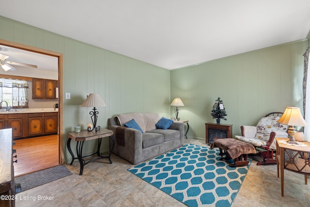 living room with ceiling fan, sink, wooden walls, and light hardwood / wood-style flooring