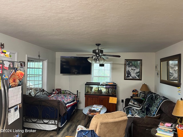 living area with ceiling fan, a textured ceiling, and wood finished floors