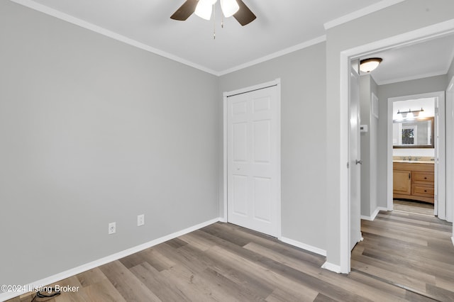 unfurnished bedroom featuring ceiling fan, ensuite bathroom, wood-type flooring, and crown molding