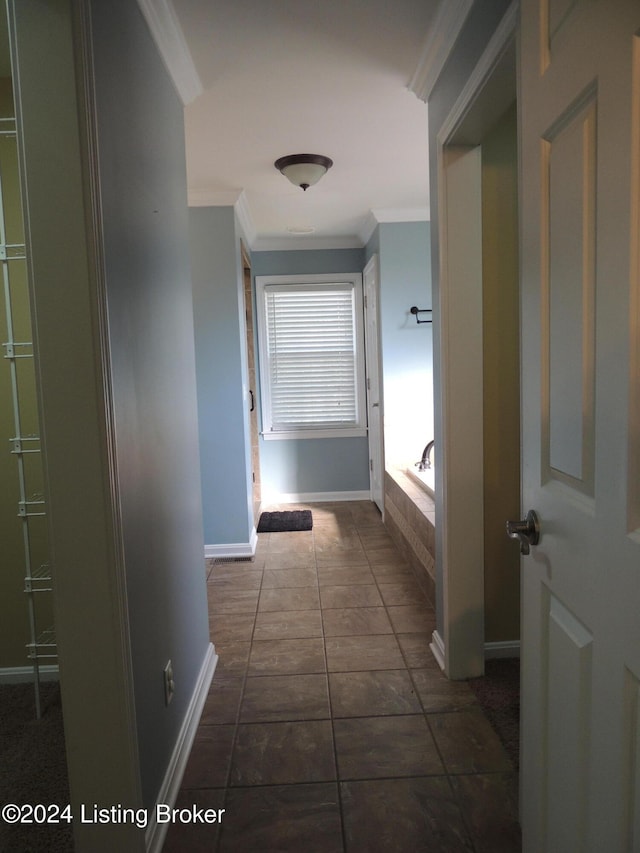 corridor featuring dark tile patterned floors and ornamental molding