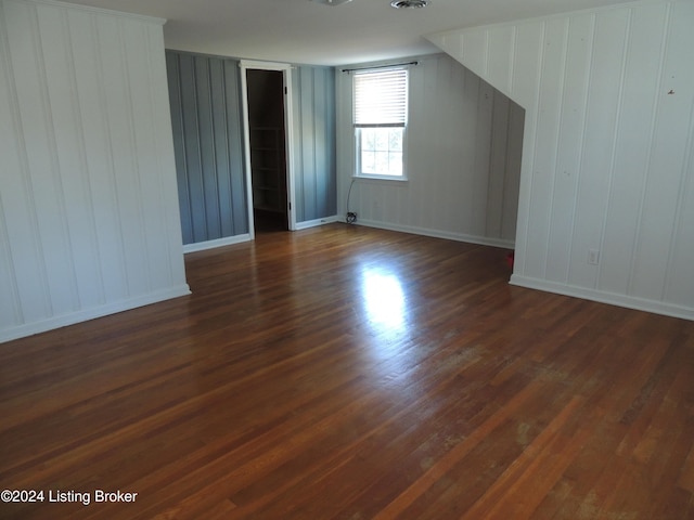 additional living space with wooden walls and dark hardwood / wood-style flooring