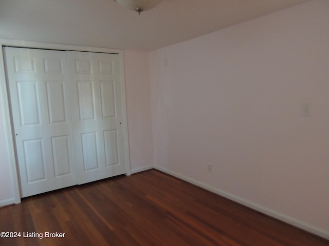 unfurnished bedroom featuring a closet and dark wood-type flooring