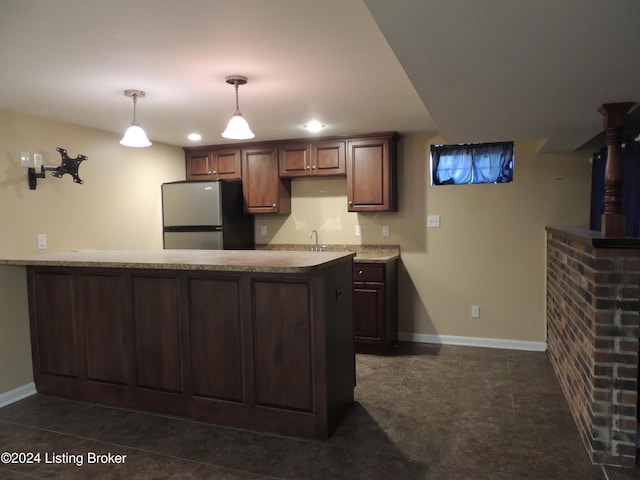 kitchen featuring kitchen peninsula, sink, dark tile patterned flooring, stainless steel refrigerator, and hanging light fixtures