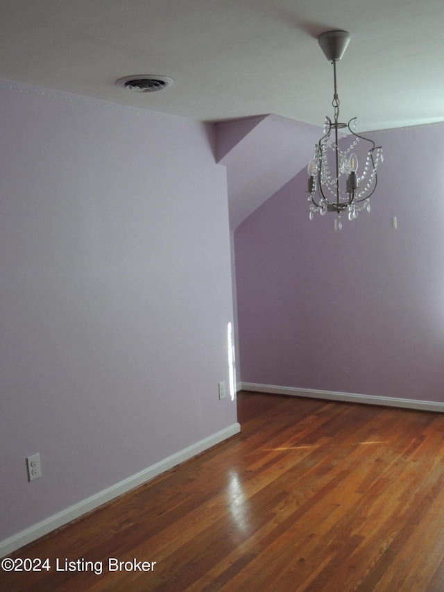 empty room featuring dark wood-type flooring and an inviting chandelier