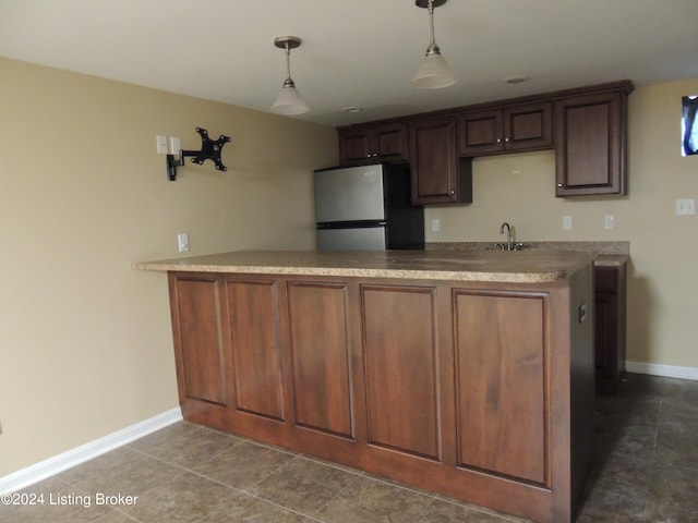 kitchen with pendant lighting, dark tile patterned flooring, sink, stainless steel fridge, and kitchen peninsula