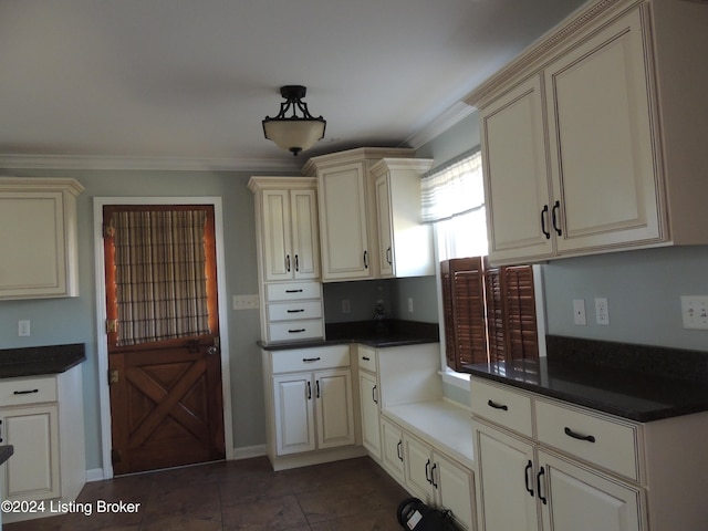 kitchen with cream cabinetry, dark tile patterned flooring, and ornamental molding