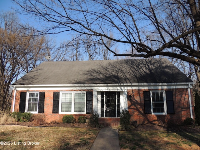 view of front facade with brick siding, a shingled roof, and a front yard