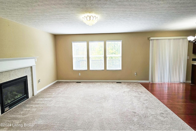 unfurnished living room with a fireplace, a textured ceiling, and hardwood / wood-style flooring