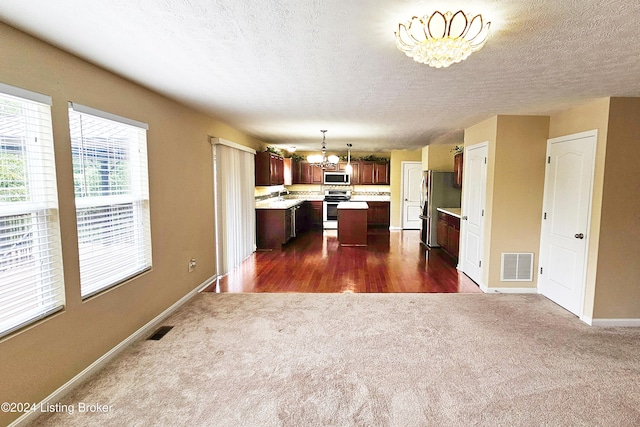 kitchen featuring a center island, stainless steel appliances, dark wood-type flooring, hanging light fixtures, and a chandelier