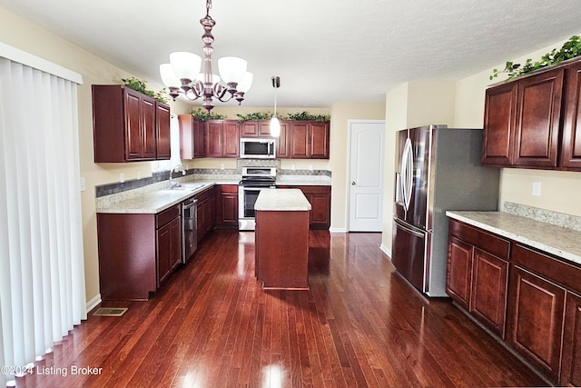 kitchen with dark hardwood / wood-style flooring, stainless steel appliances, pendant lighting, an inviting chandelier, and a kitchen island