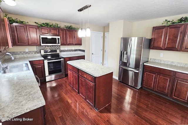 kitchen featuring sink, a center island, dark wood-type flooring, hanging light fixtures, and appliances with stainless steel finishes