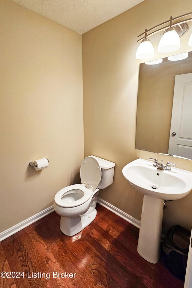 bathroom featuring wood-type flooring, a textured ceiling, and toilet