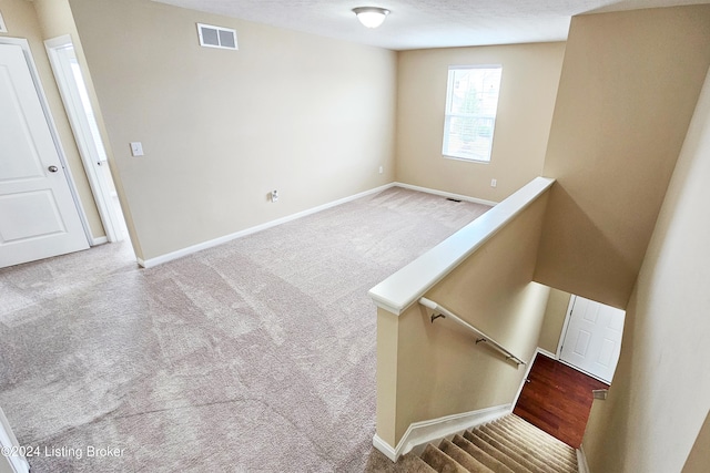 stairs featuring carpet and a textured ceiling