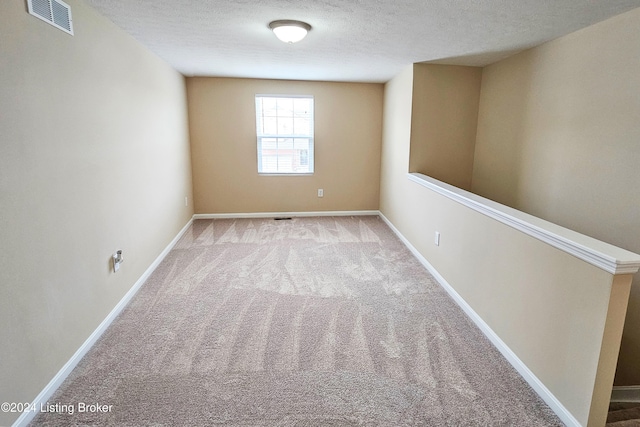 carpeted empty room featuring a textured ceiling