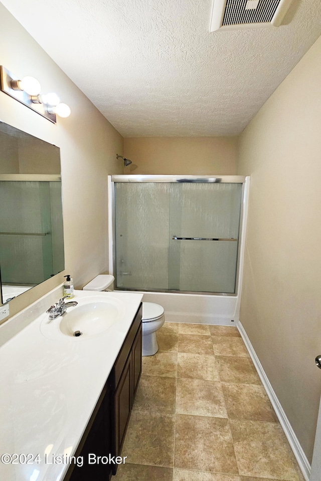 full bathroom with shower / bath combination with glass door, vanity, a textured ceiling, and toilet