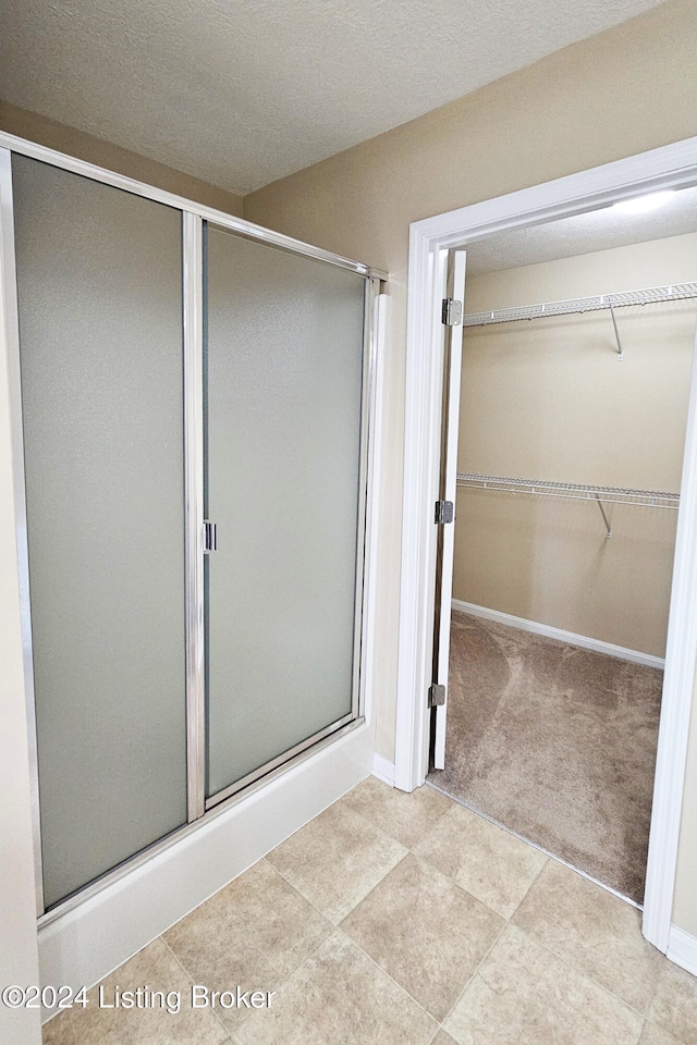 bathroom featuring a textured ceiling and walk in shower