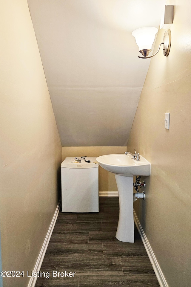 bathroom featuring hardwood / wood-style floors, lofted ceiling, and sink