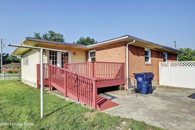 rear view of property with a deck, a patio area, and a lawn