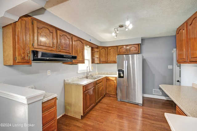 kitchen with stainless steel refrigerator with ice dispenser, a textured ceiling, sink, hardwood / wood-style floors, and range hood