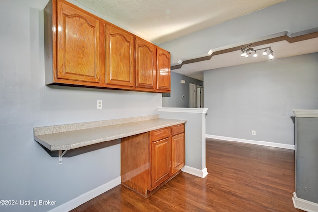 kitchen with dark hardwood / wood-style flooring, built in desk, and a textured ceiling