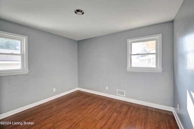 unfurnished room featuring plenty of natural light and dark wood-type flooring