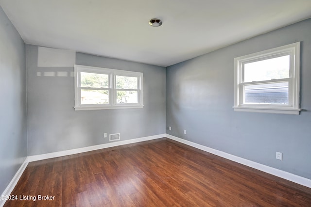 spare room featuring dark hardwood / wood-style floors and a healthy amount of sunlight