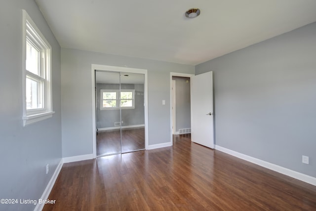 unfurnished bedroom with a closet and dark hardwood / wood-style floors