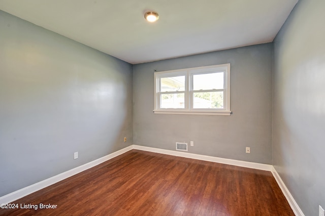 unfurnished room with dark wood-type flooring