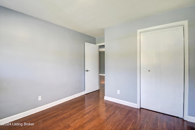 unfurnished bedroom with dark wood-type flooring and a closet