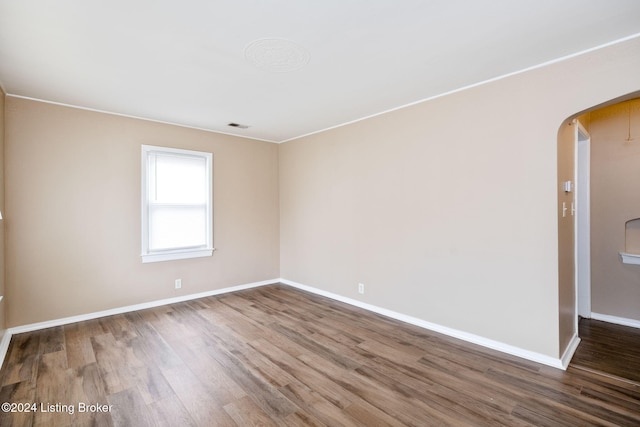 empty room featuring wood-type flooring and crown molding