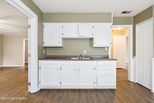 kitchen with white cabinets, a textured ceiling, dark hardwood / wood-style flooring, and sink