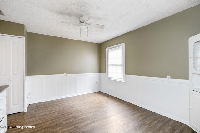 unfurnished room with ceiling fan, dark hardwood / wood-style flooring, and a textured ceiling