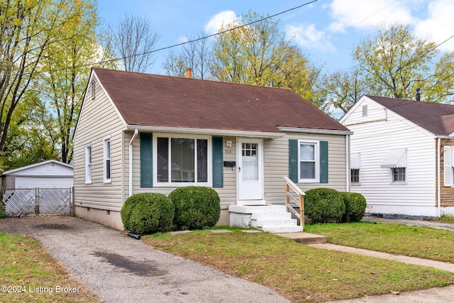 bungalow-style home with an outbuilding, a garage, and a front lawn