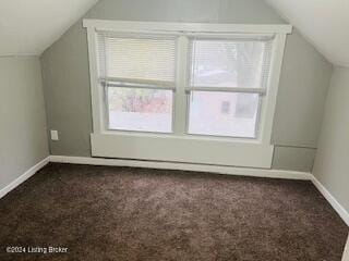 bonus room with lofted ceiling and dark colored carpet