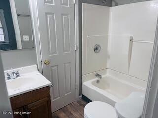 full bathroom featuring hardwood / wood-style floors, vanity, shower / bath combination, and toilet