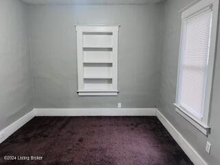 spare room with dark colored carpet