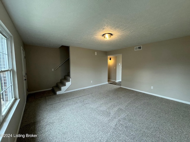 spare room featuring carpet floors and a textured ceiling