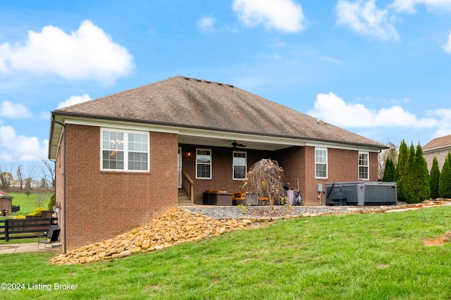 rear view of house with a lawn, ceiling fan, and a hot tub