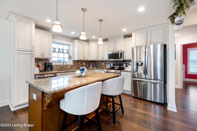 kitchen featuring a kitchen island, decorative light fixtures, dark hardwood / wood-style floors, and appliances with stainless steel finishes